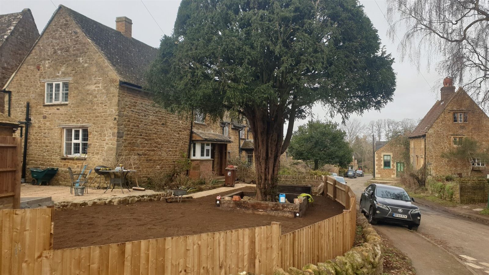 Prepared soil, timber edging around the tree and new boundary fencing.