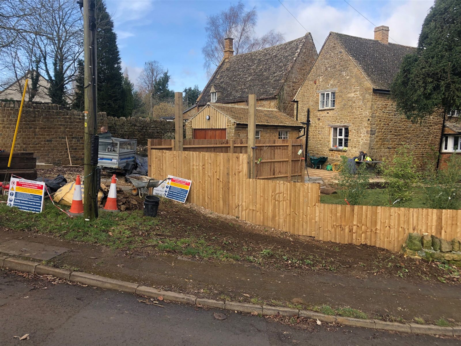 Timber fencing and planting, with landscaping work in progress beside the cottage.